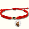 Rotes Makramee-Armband mit goldgerahmter Fotoperle / Fotolinse in der Mitte. Beispielprojektion zeigt eine Katze. Heller Hintergrund.