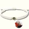 Makramee-Armband in Weiß mit einer Fotoperle / Fotolinse, eingefasst in einen goldenen Rahmen. Beispielprojektion zeigt eine Familie im Winter. Heller Hintergrund.