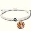 Makramee-Armband in Weiß mit einer schwarzen Fotoperle / Fotolinse, eingefasst in einen schwarzen Rahmen. Beispielprojektion zeigt eine Familie beim Wandern. Heller Hintergrund.