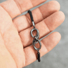 Ein handgehaltenes schwarzes Infinity-Armband mit einer eingebauten Fotolinse, durch die ein eingefangenes Bild projiziert werden kann, dargestellt in der Handfläche einer Person.